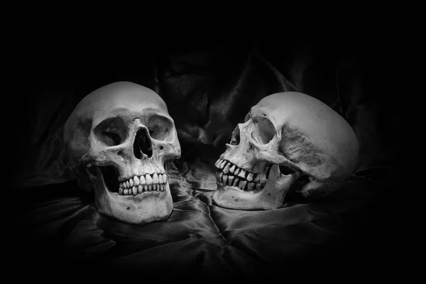 Crâne avec un bouquet de fleurs et de lumière de bougie sur une table en bois avec un fond noir la nuit en noir et blanc / Nature morte — Photo
