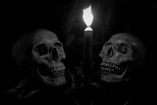 Calavera con ramo de flores y luz de vela en mesa de madera con fondo negro en tiempo nocturno en blanco y negro / Naturaleza muerta — Foto de Stock