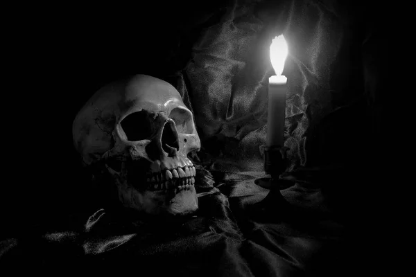 Calavera con ramo de flores y luz de vela en mesa de madera con fondo negro en tiempo nocturno en blanco y negro / Naturaleza muerta — Foto de Stock