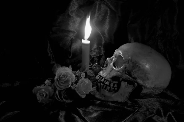 Calavera con ramo de flores y luz de vela en mesa de madera con fondo negro en tiempo nocturno en blanco y negro / Naturaleza muerta — Foto de Stock