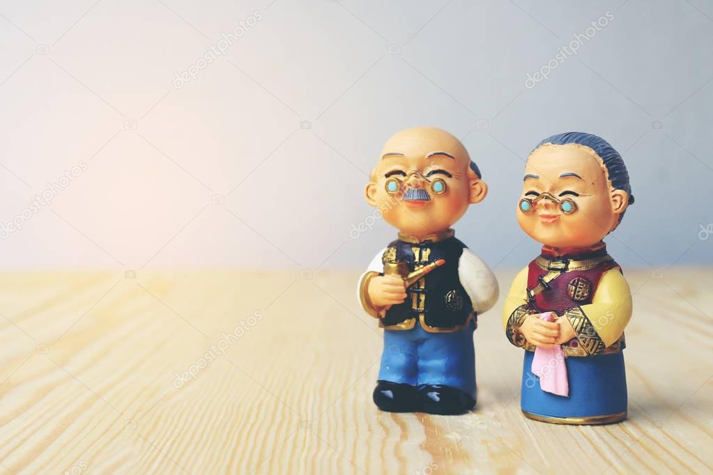 Grandma and grandpa dolls in chinese uniform style standing on wooden background. in chinese new year