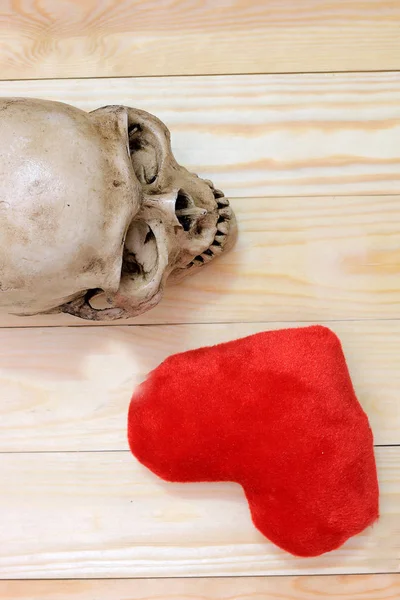 Crânio humano com coração vermelho no fundo de madeira, vista superior. Natureza morta Imagem e foco selecionado — Fotografia de Stock