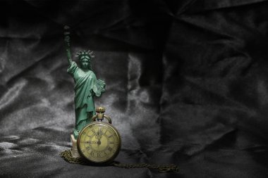 Özgürlük heykeli ile siyah kumaş arka plan üzerinde vintage cep saati. Natürmort fotoğraf