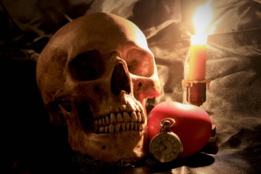 insan kafatası vintage cep saati, kırmızı kalp ve mum ışığı natürmort fotoğraf siyah kumaş arka plan, sevgi ve zaman kavramı ile.