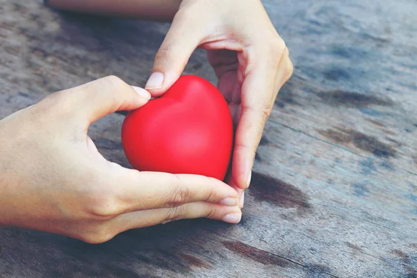 Mani femminili che danno cuore rosso. tono vintage — Foto Stock