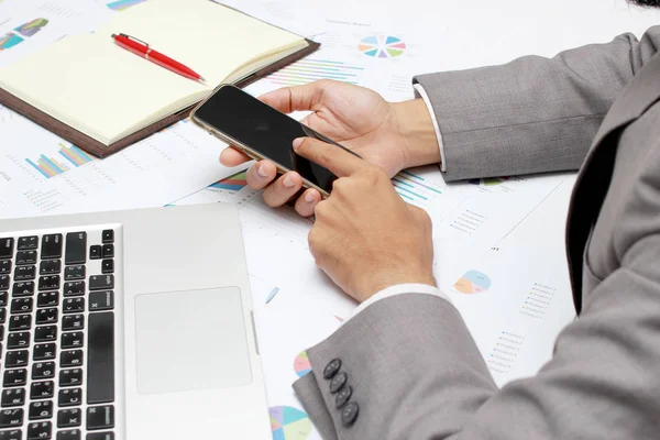 Руки бізнесмена зайняті використовуючи мобільний телефон, ноутбук, ручку і блокнот на офісному столі. Аналіз графіків і графіків, що показують результати їх успішної командної роботи. Концепція бізнесу — стокове фото
