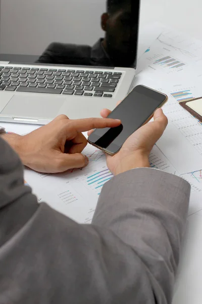 ビジネス男の手が忙しいオフィスの机で携帯電話、ノート パソコン、ペンとノートを使用して。分析グラフと、抜群のチームワークの結果を示すグラフ。ビジネス コンセプト — ストック写真