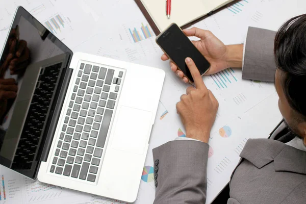 Homem de negócios mãos ocupadas usando telefone celular, laptop, caneta e notebook na mesa de escritório. Analise os gráficos e gráficos que mostram os resultados de seu trabalho em equipe bem sucedido. Conceito de negócio — Fotografia de Stock