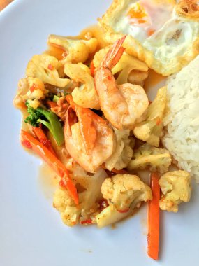 fasulye ve pilav ve kızarmış yumurta ahşap arka plan üzerinde beyaz tabak karides sebzeler ile tavada. Tay tarzında gıda.