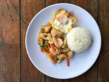 fasulye ve pilav ve kızarmış yumurta ahşap arka plan üzerinde beyaz tabak karides sebzeler ile tavada. Tay tarzında gıda.