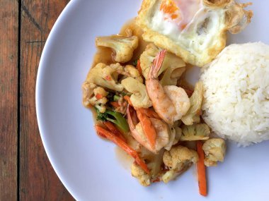 fasulye ve pilav ve kızarmış yumurta ahşap arka plan üzerinde beyaz tabak karides sebzeler ile tavada. Tay tarzında gıda.