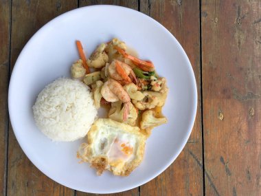 fasulye ve pilav ve kızarmış yumurta ahşap arka plan üzerinde beyaz tabak karides sebzeler ile tavada. Tay tarzında gıda.