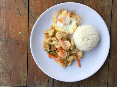 fasulye ve pilav ve kızarmış yumurta ahşap arka plan üzerinde beyaz tabak karides sebzeler ile tavada. Tay tarzında gıda.