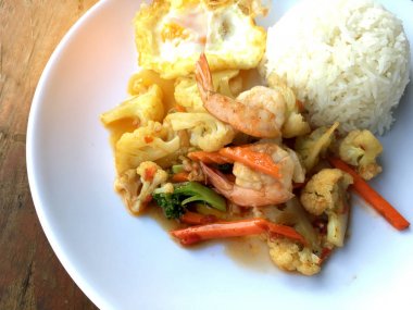 fasulye ve pilav ve kızarmış yumurta ahşap arka plan üzerinde beyaz tabak karides sebzeler ile tavada. Tay tarzında gıda.