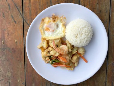 fasulye ve pilav ve kızarmış yumurta ahşap arka plan üzerinde beyaz tabak karides sebzeler ile tavada. Tay tarzında gıda.