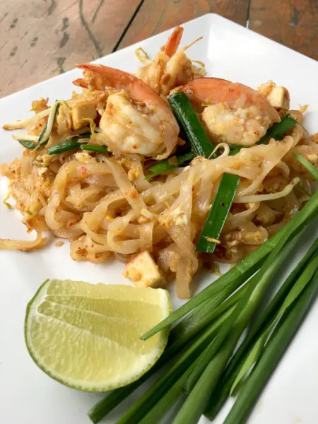 Fideos fritos tailandeses "Pad Thai" con camarones y verduras en plato blanco sobre fondo de madera. El plato principal nacional de Tailandia. la comida popular en Tailandia. Fideos fritos tailandeses . — Foto de Stock