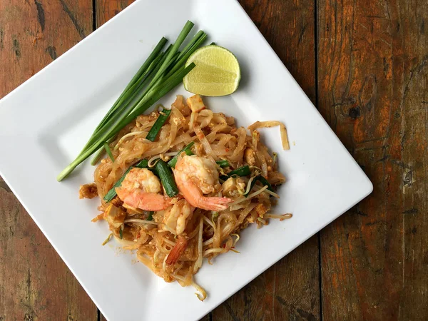 Tay Fried Noodle "Pad Thai" karides ve beyaz tabakta sebze ile arka plan woodden. Tayland'ın ulusal ana yemek biri. Tayland popüler gıda. Tayland kızarmış noodle. — Stok fotoğraf