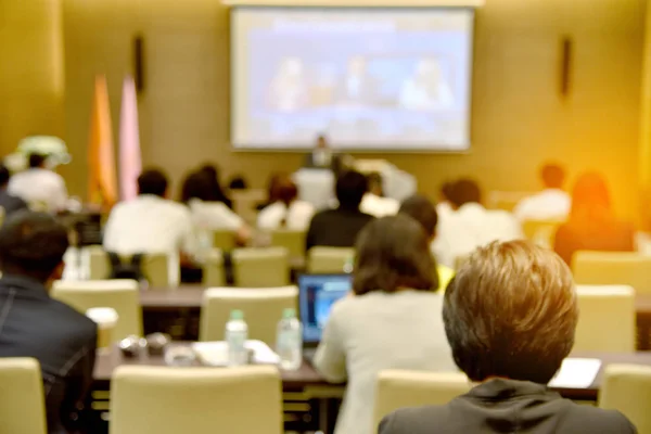 Blurred image of education people, business people and students sitting in large hal with screen and projector for showing information — Stock Photo, Image