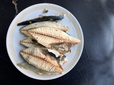 siyah arka plan üzerine beyaz tabak uskumru.