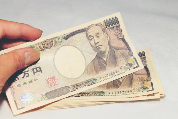 Elini tut 10000 Japon para birimi, beyaz arka plan, bir kopya alanı üzerinde bir timsah doku cüzdan, bill yen.