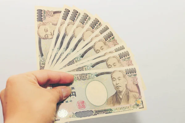 Main tenant une monnaie japonaise 10000, billet yen dans une texture crocodile Portefeuille, sur fond blanc, un espace de copie . — Photo