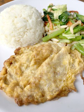Kızarmış sebze Tay omlet (yumurta) ile pirinç rustik ahşap arka plan üzerinde beyaz plaka ile karıştırın. Vejetaryen yiyecekler, sağlıklı gıda.