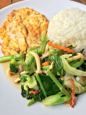 Kızarmış sebze Tay omlet (yumurta) ile pirinç rustik ahşap arka plan üzerinde beyaz plaka ile karıştırın. Vejetaryen yiyecekler, sağlıklı gıda.