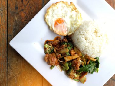 kavrulmuş chili Yapıştır ve tatlı fesleğen yaprağı, brokoli, mantar karışık sebze, kızarmış tavukla karıştırın kızarmış yumurta beyaz ahşap arka plan, gıda Tay tabakta Yasemin pirinç.