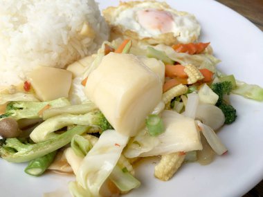 Tofu ve ahşap arka plan üzerinde beyaz tabak pirinç kızarmış yumurta ile tavada kızartılmış karışık sebze. Vejetaryen yiyecekler, sağlıklı gıda.