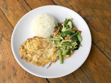 Kızarmış sebze Tay omlet (yumurta) ile pirinç rustik ahşap arka plan üzerinde beyaz plaka ile karıştırın. Vejetaryen yiyecekler, sağlıklı gıda.