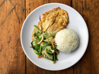 Kızarmış sebze Tay omlet (yumurta) ile pirinç rustik ahşap arka plan üzerinde beyaz plaka ile karıştırın. Vejetaryen yiyecekler, sağlıklı gıda.