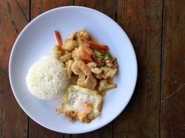 fasulye ve pilav ve kızarmış yumurta ahşap arka plan üzerinde beyaz tabak karides sebzeler ile tavada. Tay tarzında gıda.