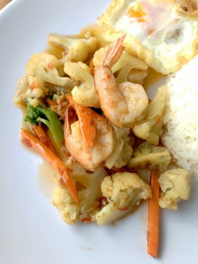 fasulye ve pilav ve kızarmış yumurta ahşap arka plan üzerinde beyaz tabak karides sebzeler ile tavada. Tay tarzında gıda.