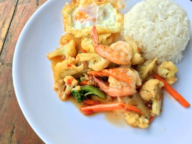 fasulye ve pilav ve kızarmış yumurta ahşap arka plan üzerinde beyaz tabak karides sebzeler ile tavada. Tay tarzında gıda.