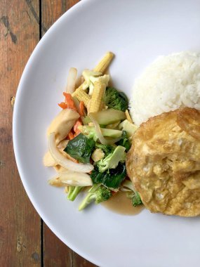 Ahşap arka plan beyaz bir tabağa omlet ile kızartma sebze ilave edin. Tay tarzı yiyecek. Vejetaryen yiyecekler