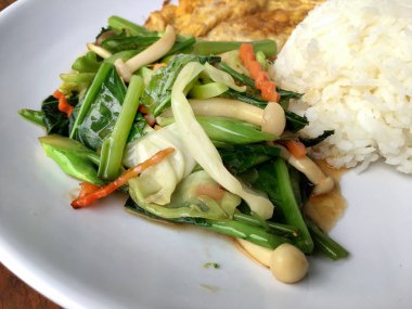 Kızarmış sebze Tay omlet (yumurta) ile pirinç rustik ahşap arka plan üzerinde beyaz plaka ile karıştırın. Vejetaryen yiyecekler, sağlıklı gıda.