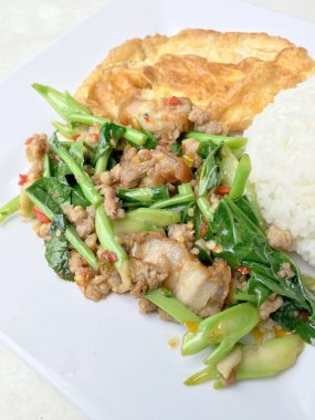 Fried Çince lahana istiridye soslu ve baharatlı domuz beyaz tabak pirinç ve Tay omlet ile kıyılmış. Tay tarzında gıda.