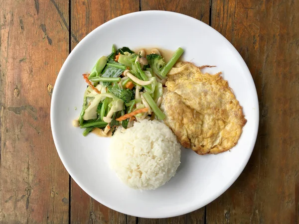 Aduk sayuran goreng dengan Thai Omelette (orak-arik telur) dengan nasi di piring putih pada latar belakang kayu pedesaan. Makanan vegetarian, makanan sehat . — Stok Foto