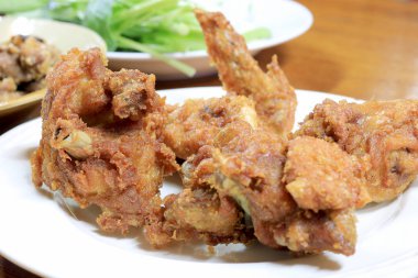 Baharatlı derin kızartma tava tavuk kanadı beyaz tabak yemek için masaya.