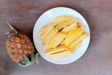 Taze kesme ananas ve ananas kabuklu Asya tarzı eski ahşap arka plan üzerinde beyaz tabak içinde. Tropikal meyve kavramı.