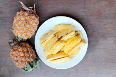 Taze kesme ananas ve ananas kabuklu Asya tarzı eski ahşap arka plan üzerinde beyaz tabak içinde. Tropikal meyve kavramı.