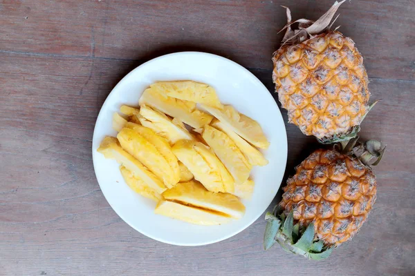 Snijden van verse ananas en ananas gepeld Aziatische stijl in witte schaal op de oude houten achtergrond. Tropisch fruit concept. — Stockfoto