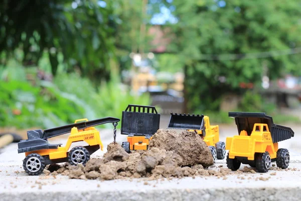 Carro de brinquedo caminhão com areia e solo no piso de concreto com desfoque boken equipamento de construção ambiente verde no trabalho, conceito de construção, foco seletivo . — Fotografia de Stock