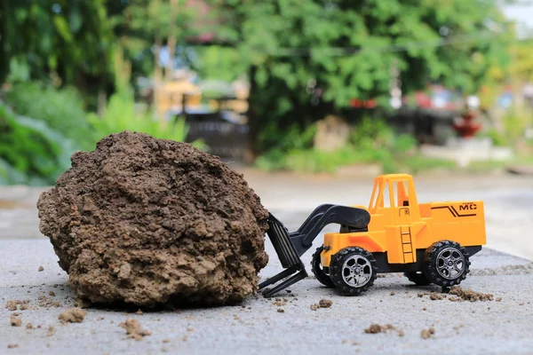 Truck toy car with sand and soil on the concrete floor with blur boken green environment  construction equipment at work ,construction concept, selective focus. — Stock Photo, Image