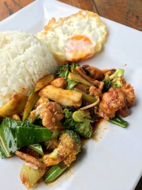 kavrulmuş chili Yapıştır ve tatlı fesleğen yaprağı, brokoli, mantar karışık sebze, kızarmış tavukla karıştırın kızarmış yumurta beyaz ahşap arka plan, gıda Tay tabakta Yasemin pirinç.