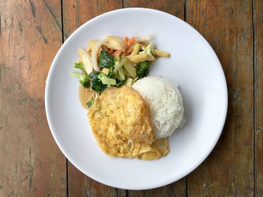 Ahşap arka plan beyaz bir tabağa omlet ile kızartma sebze ilave edin. Tay tarzı yiyecek. Vejetaryen yiyecekler