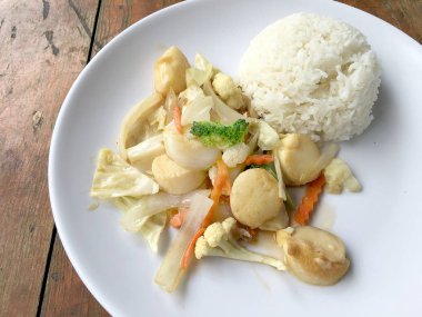 Kızarmış tofu sebze ile Tayland Yasemin pirinç ahşap arka plan üzerinde beyaz tabak ile. Gıda Tay tarzında. Vejetaryen yiyecekler.