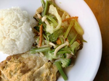 Kızarmış sebze Tay omlet (yumurta) ile pirinç rustik ahşap arka plan üzerinde beyaz plaka ile karıştırın. Vejetaryen yiyecekler, sağlıklı gıda.