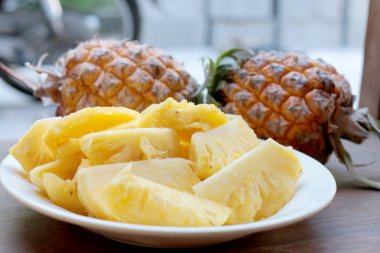Taze kesme ananas ve ananas kabuklu Asya tarzı eski ahşap arka plan üzerinde beyaz tabak içinde. Tropikal meyve kavramı.