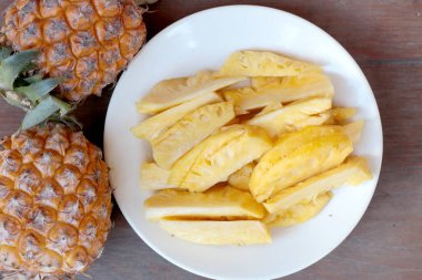 Taze kesme ananas ve ananas kabuklu Asya tarzı eski ahşap arka plan üzerinde beyaz tabak içinde. Tropikal meyve kavramı.